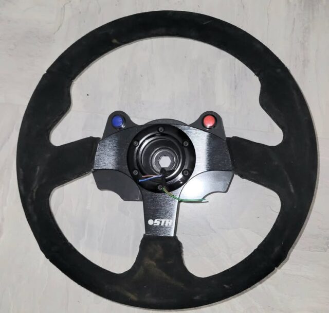 It's great to be able to design and make stuff in house. Whilst this is a simple bracket it does move me forward on this job (with man flu!)

It's a simple steering wheel plate for switches and rotary knobs. I 2d scanned the steering wheel to get the profile of the spokes, imported that into CAD to create the right shape for the backplate and then created the GCode for the CNC machine. This has been made in 6mm ABS which may be a bit OTT but it's strong! 
I haven't received the rotary knobs yet (boost, map, rear diff and a spare) so marked up the rear of the bracket ready to create the correct size holes.